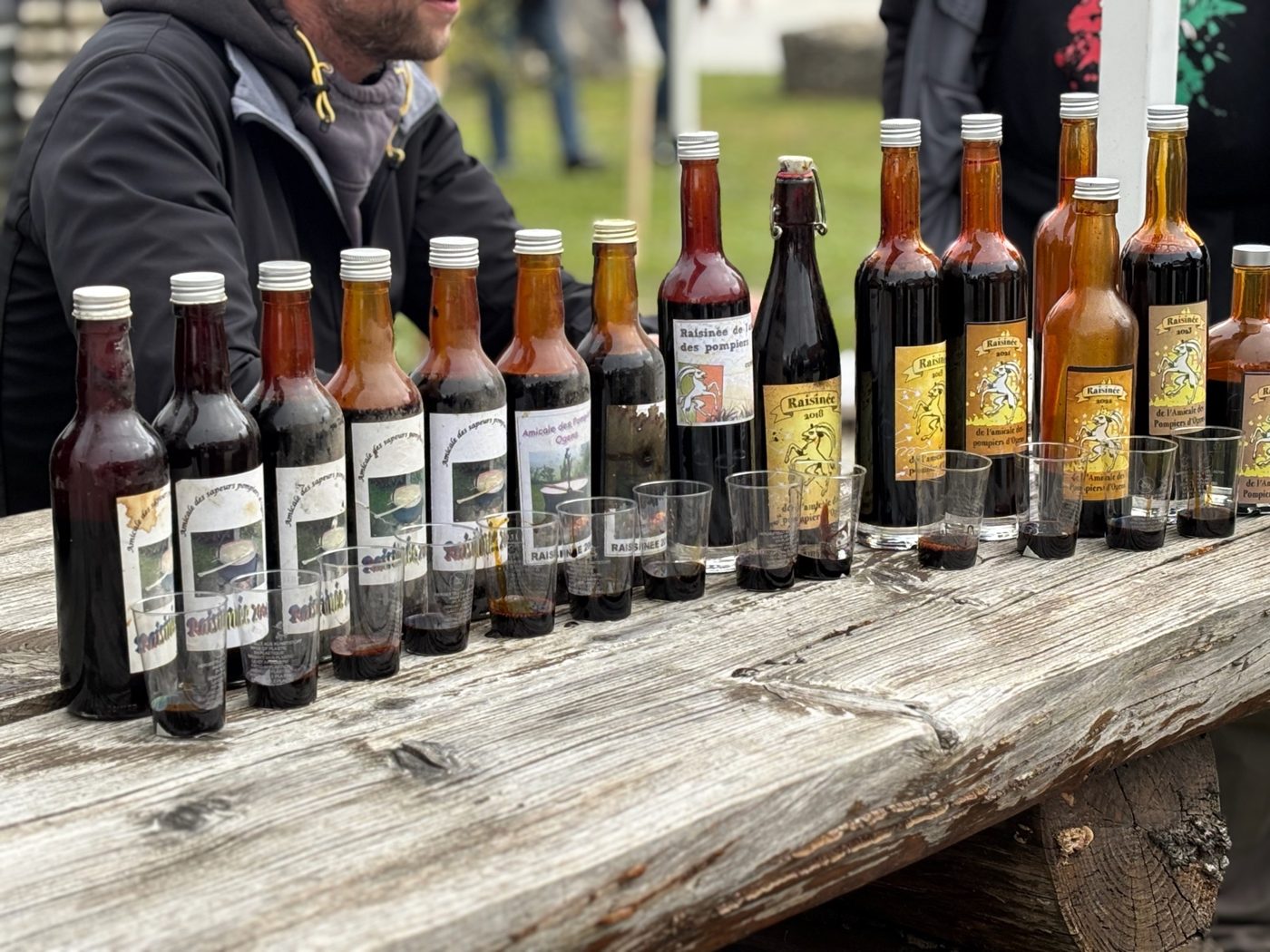 Des bouteilles de raisinée 2025 alignées sur une table en bois, avec leur étiquette au bouc