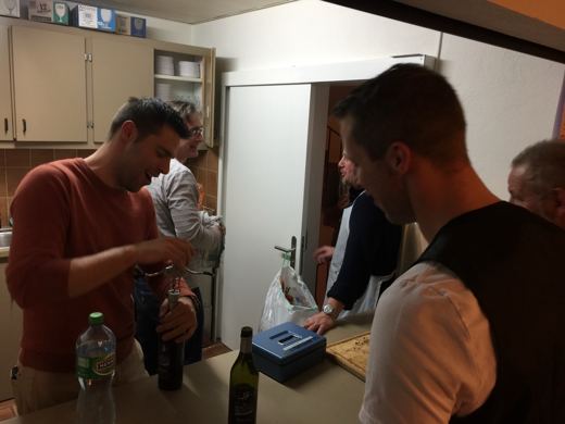 Homme de dos et de profil penche sur une table de service dans une salle communale.