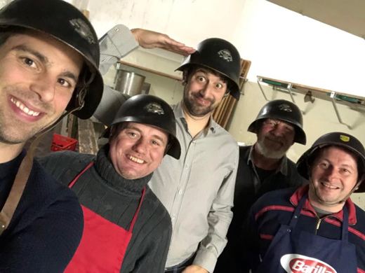 Selfie de cinq membres de l'amicale portant des casques de pompier et souriant, pris dans une cuisine.