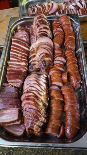 Plateau de saucisses crues et de pièces fumées disposées en cercle, prêtes à être cuisinées pour la choucroute garnie.