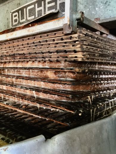 Claies métalliques empilées d'un pressoir avec du jus de pomme qui s'écoule entre elles