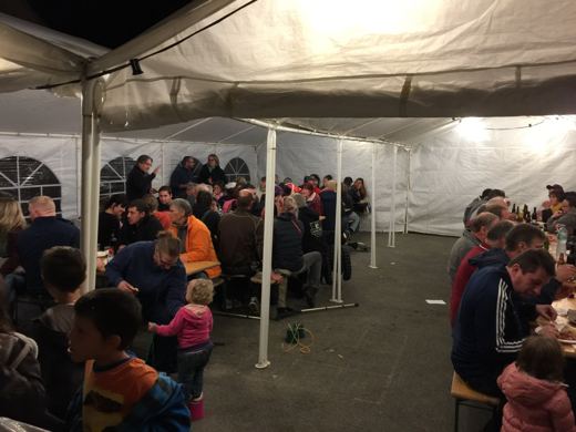 Intérieur d'une tente le soir avec des familles et des enfants attablés autour de plusieurs tables