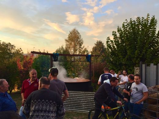 Groupe de personnes rassemblées autour d'un chaudron fumant au coucher du soleil, un vélo posé à côté