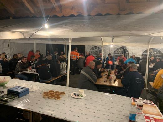 Intérieur d'une tente le soir avec des convives attablés et une assiette de biscuits au premier plan