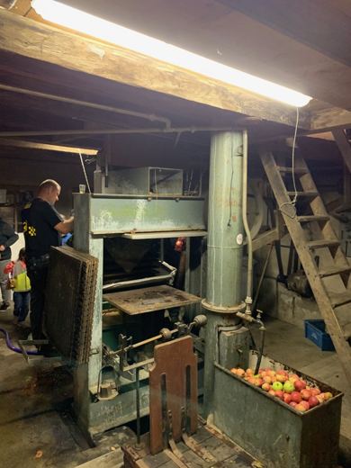 Intérieur d'une grange avec un pressoir ancien et une caisse de pommes rouges et vertes au premier plan
