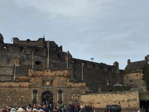 Esplanade du château d'Édimbourg sous un ciel gris, groupe de visiteurs massés près des remparts.