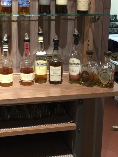 Étagère en verre présentant plusieurs bouteilles de whisky écossais, prête pour une dégustation.