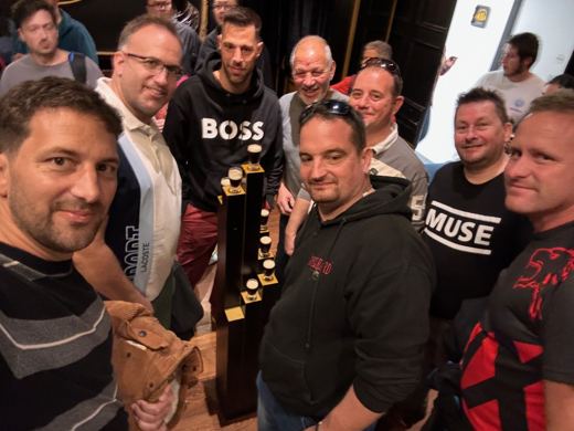 Groupe d'hommes en tee-shirts assortis posant ensemble et souriant, à l'intérieur d'un grand hall.