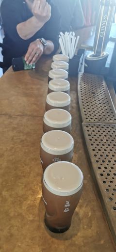 Rangée de pintes de bière brune Guinness alignées sur un comptoir de bar.