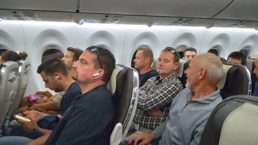 Intérieur de cabine d'avion avec plusieurs hommes assis côte à côte pendant le vol.