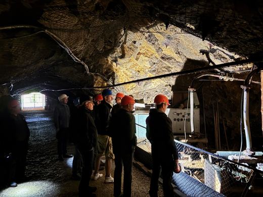 Groupe de visiteurs coiffés de lampes frontales avançant dans une galerie de mine d'asphalte faiblement éclairée.